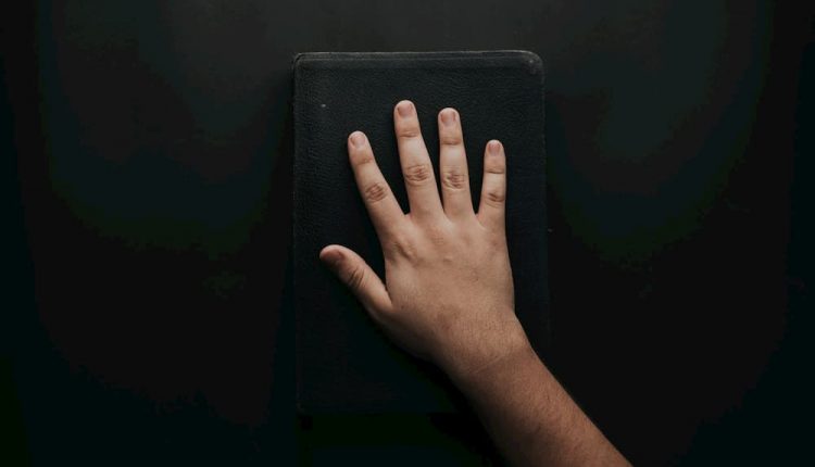 pessoa-com-a-mao-na-biblia